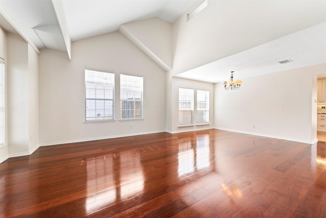 empty room featuring wood finished floors, baseboards, visible vents, high vaulted ceiling, and a chandelier