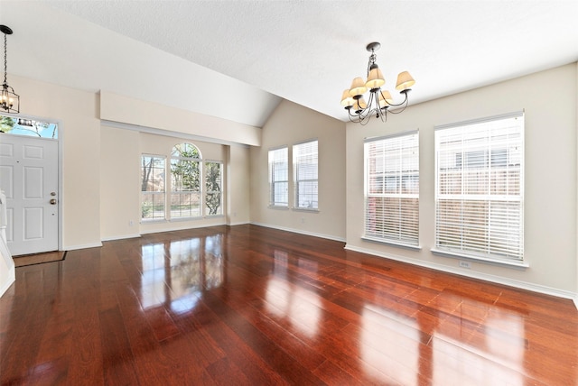 entryway featuring a chandelier, vaulted ceiling, baseboards, and wood finished floors