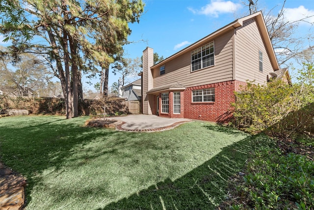 back of property with a lawn, a fenced backyard, brick siding, a chimney, and a patio area