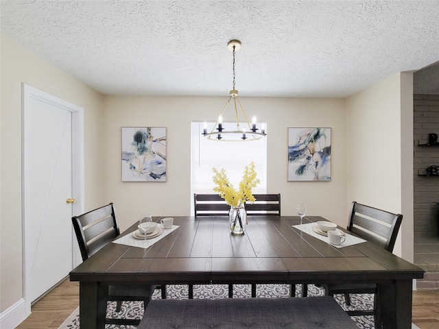 dining area featuring light wood-style flooring, a notable chandelier, and a textured ceiling