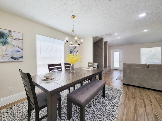 dining space with a notable chandelier, light wood-style flooring, a textured ceiling, recessed lighting, and baseboards