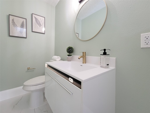 bathroom with vanity, toilet, baseboards, and marble finish floor