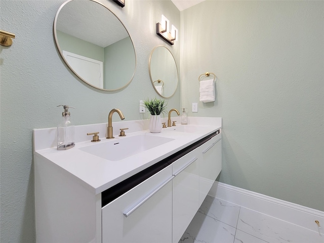 bathroom with double vanity, marble finish floor, baseboards, and a sink