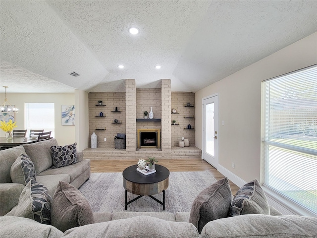 living area featuring plenty of natural light, wood finished floors, an inviting chandelier, and vaulted ceiling