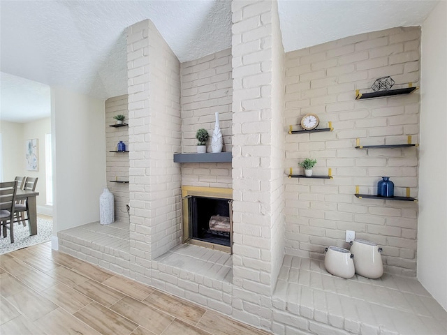 bathroom featuring a tile shower, a brick fireplace, and a textured ceiling