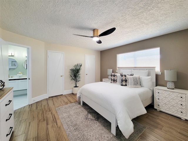 bedroom featuring light wood finished floors, connected bathroom, baseboards, and a ceiling fan