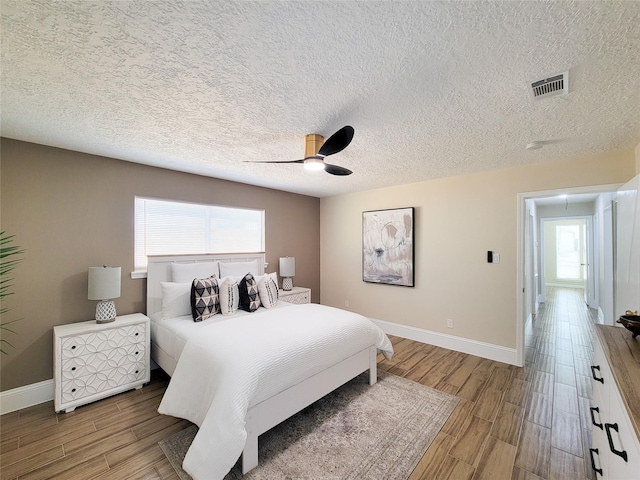 bedroom with visible vents, baseboards, ceiling fan, and wood finished floors