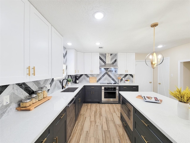 kitchen featuring white cabinetry, stainless steel appliances, wall chimney exhaust hood, and a sink