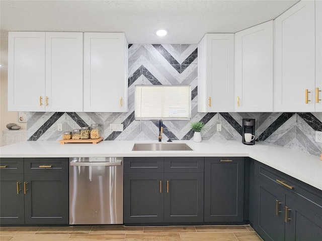 kitchen featuring a sink, stainless steel dishwasher, light countertops, and white cabinetry