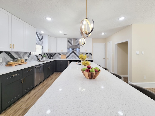 kitchen featuring backsplash, wall chimney range hood, dark cabinetry, white cabinetry, and stainless steel dishwasher