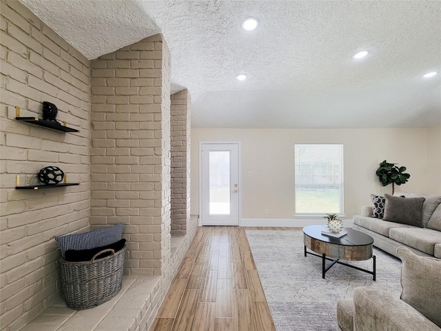 living area with baseboards, recessed lighting, a textured ceiling, and light wood-style floors