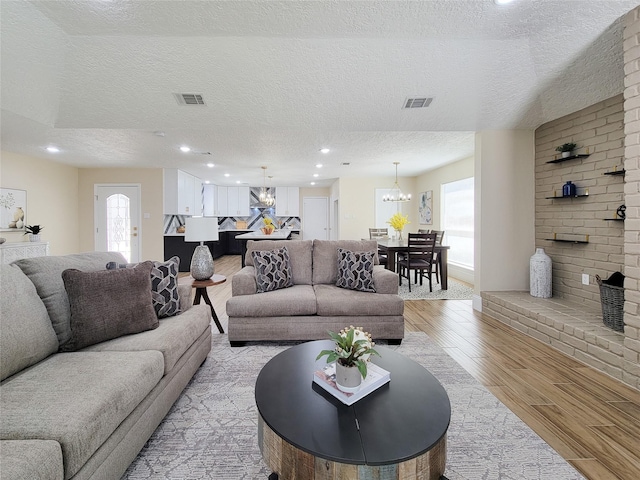 living room featuring an inviting chandelier, light wood-style flooring, recessed lighting, and visible vents