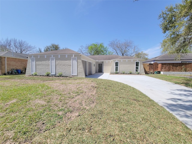 view of front of home featuring brick siding, driveway, a front lawn, and fence