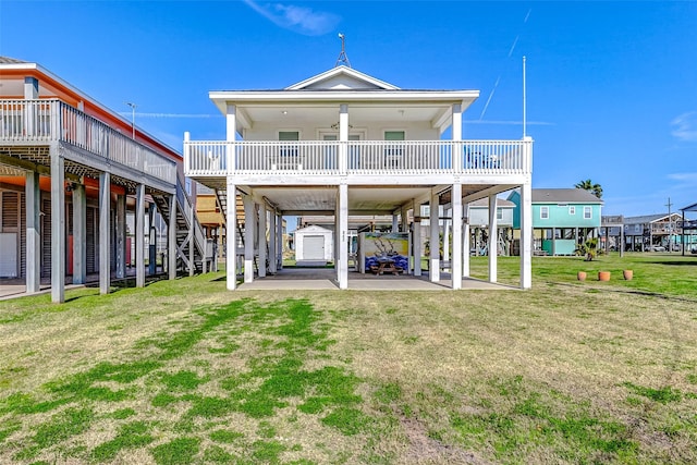 rear view of property with stairs, an outbuilding, a carport, and a lawn