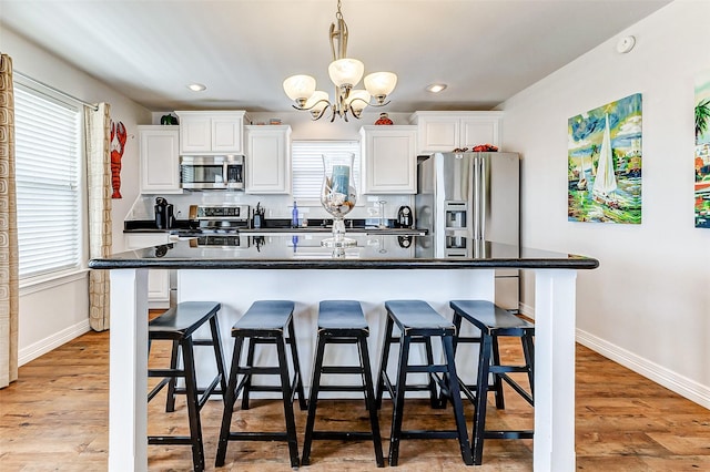 kitchen with stainless steel appliances, a kitchen bar, backsplash, and white cabinets