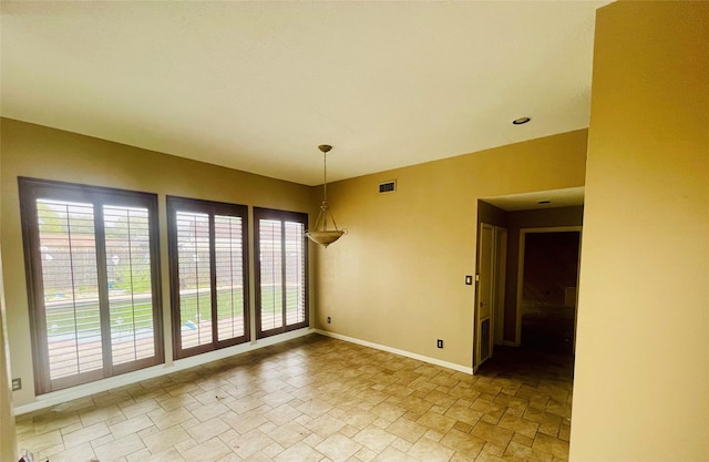 empty room with visible vents, stone finish floor, and baseboards