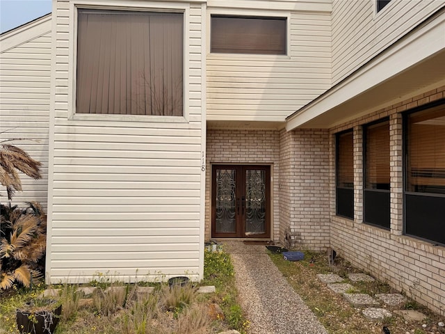 view of exterior entry with brick siding and french doors