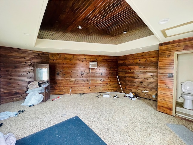 interior space featuring a raised ceiling, wooden walls, and wood ceiling