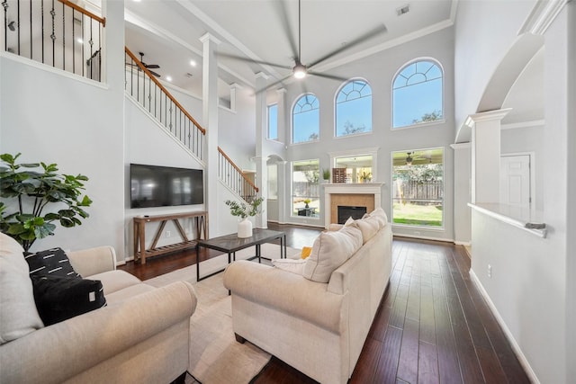 living area with visible vents, baseboards, decorative columns, arched walkways, and dark wood-style floors