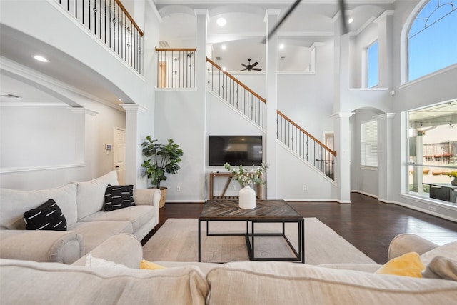 living room featuring wood finished floors, stairs, ceiling fan, and decorative columns