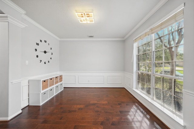 empty room with a wainscoted wall, crown molding, visible vents, and wood-type flooring