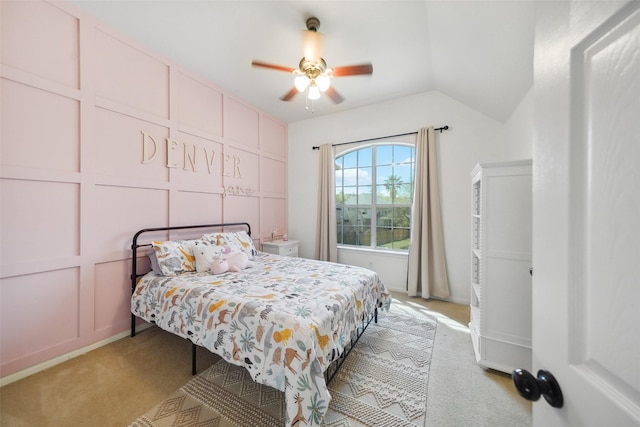 bedroom with vaulted ceiling, a decorative wall, a ceiling fan, and light carpet