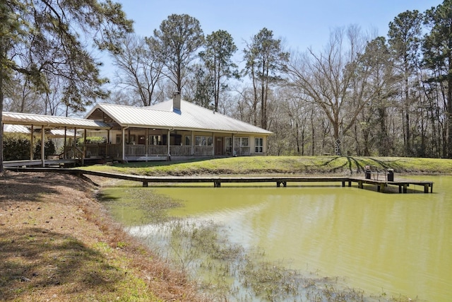 exterior space featuring metal roof, a water view, and a chimney