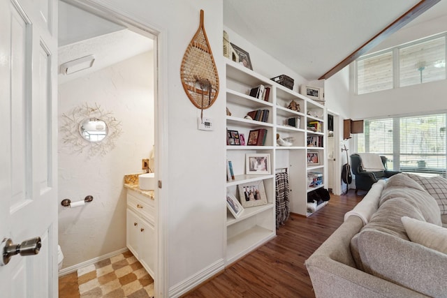 living area featuring light wood-type flooring, baseboards, and vaulted ceiling