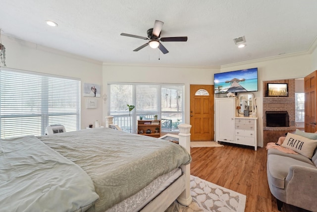 bedroom featuring visible vents, multiple windows, a fireplace, and wood finished floors