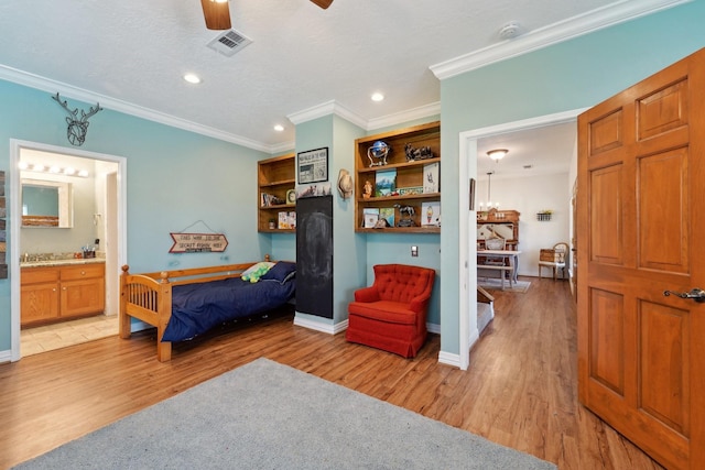 bedroom with baseboards, visible vents, light wood finished floors, and ornamental molding