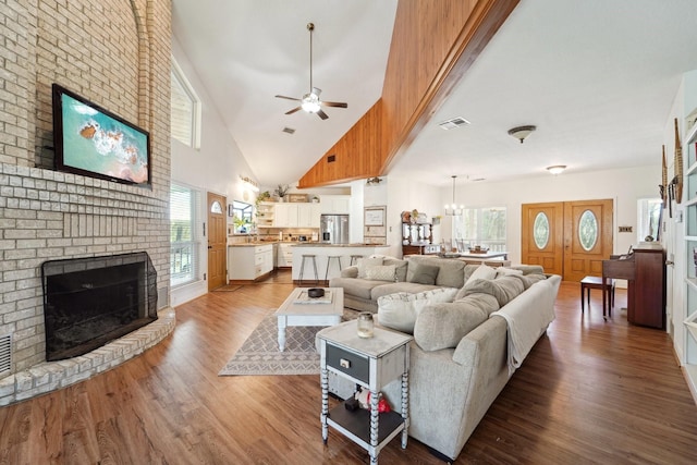 living room with a fireplace, wood finished floors, ceiling fan with notable chandelier, and a wealth of natural light