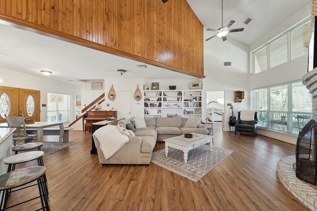 living room with a ceiling fan, stairs, wood finished floors, and visible vents