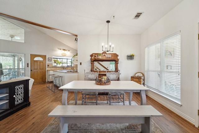 dining space with a wealth of natural light, visible vents, a chandelier, and vaulted ceiling