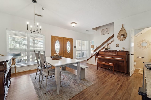 dining room featuring visible vents, baseboards, a notable chandelier, and wood finished floors