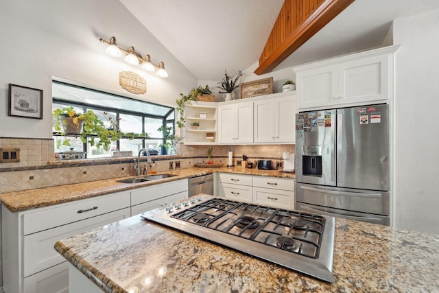 kitchen with lofted ceiling, a sink, white cabinets, appliances with stainless steel finishes, and backsplash