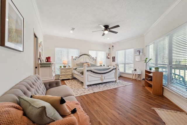 bedroom featuring a textured ceiling, wood finished floors, and crown molding