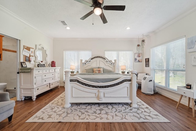 bedroom featuring visible vents, ornamental molding, a textured ceiling, a ceiling fan, and dark wood-style flooring