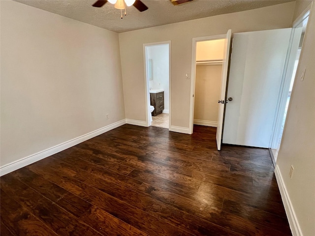 unfurnished bedroom featuring dark wood-style floors, baseboards, ensuite bathroom, and a textured ceiling