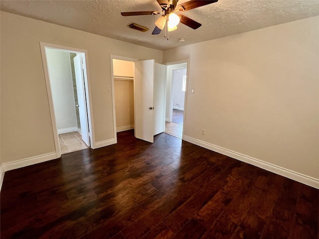 unfurnished bedroom featuring dark wood finished floors, baseboards, visible vents, and a textured ceiling