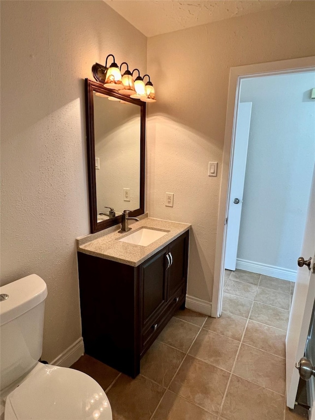 bathroom featuring tile patterned flooring, toilet, vanity, and baseboards