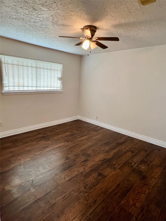 unfurnished room featuring baseboards, dark wood-type flooring, a ceiling fan, and a textured ceiling