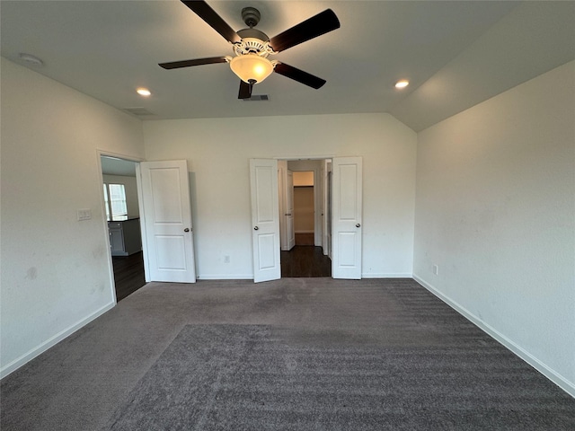 unfurnished bedroom featuring visible vents, a ceiling fan, dark colored carpet, baseboards, and vaulted ceiling