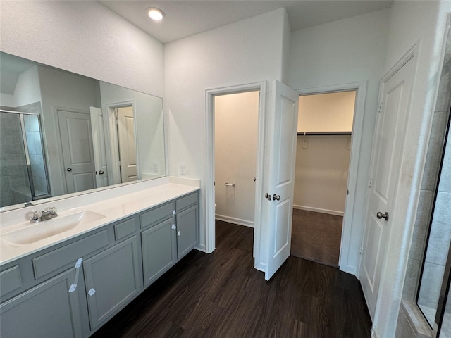 bathroom with a spacious closet, recessed lighting, a stall shower, wood finished floors, and vanity