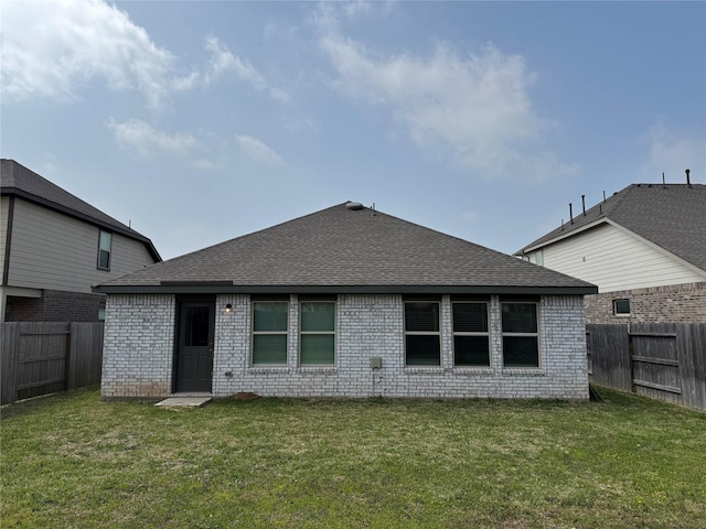 back of house featuring a yard, a fenced backyard, and roof with shingles