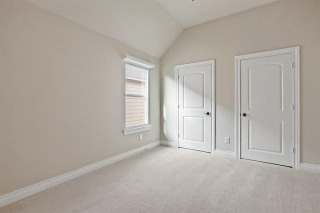 unfurnished bedroom featuring carpet floors, baseboards, and vaulted ceiling