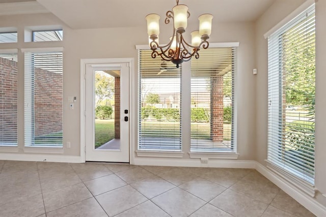 doorway featuring light tile patterned flooring, a chandelier, and healthy amount of natural light