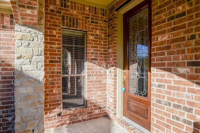 view of exterior entry featuring brick siding