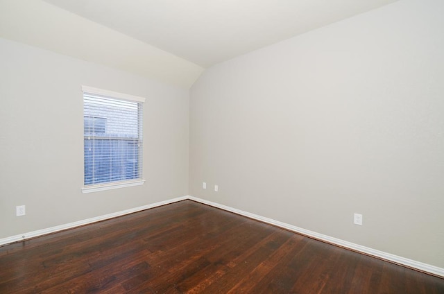 spare room featuring baseboards, lofted ceiling, and wood finished floors