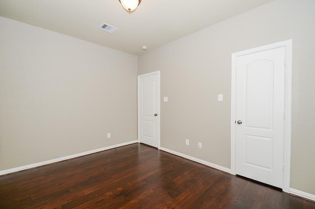 empty room featuring visible vents, baseboards, and dark wood-type flooring