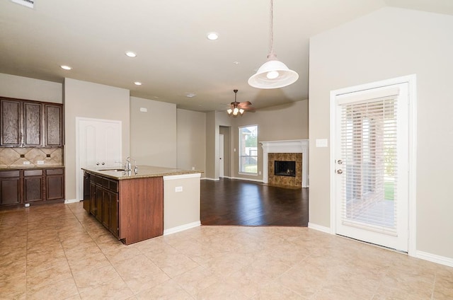 kitchen featuring baseboards, a fireplace, ceiling fan, pendant lighting, and backsplash